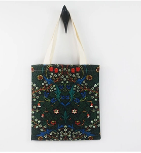 Detail of William Morris floral canvas tote bag with cream handles on a black background