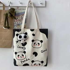 Detail der weißen Panda-Stofftasche mit süßen Drucken und Plüsch-Panda-Schlüsselanhänger
