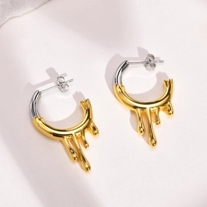 Close-up of irregular two-tone C-shape earrings with gold and silver fluid drip design