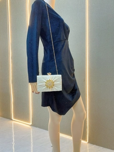 Detail der weißen Seiden-Abendtasche mit Plisseestruktur und großer Goldkristallblume
