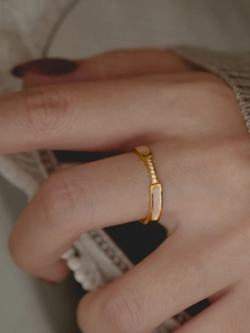 Detailed close-up of golden titanium ring with white shell inlay and zircon accents