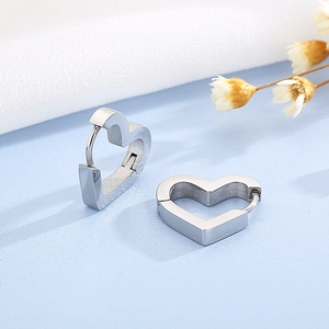 Polished silver heart-shaped stainless steel hoop earrings for women on a blue surface