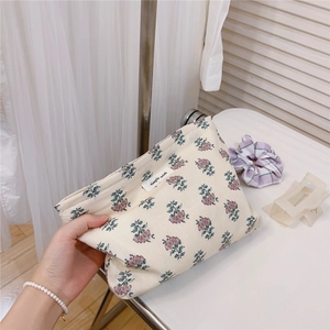 Detail of vintage floral cotton makeup bag held by hand, showing soft fabric and tag