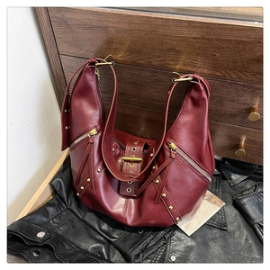 Detail of burgundy vintage crossbody bag with gold rivets and matte leather texture