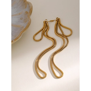 Macro shot of gold-plated wavy snake chain tassel earrings on a textured shell background