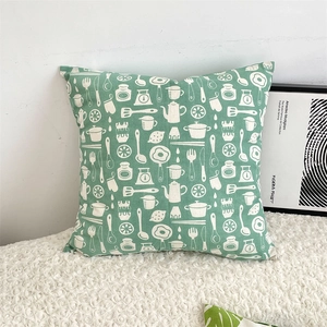 Detail of green cotton linen pillow cover with white kitchen utensils pattern on white fur
