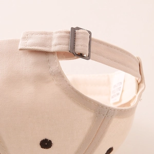 Detail of adjustable metal buckle and embroidery on the beige cotton baseball cap