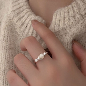Close-up of 925 sterling silver ring with white pearl and braided band on a finger