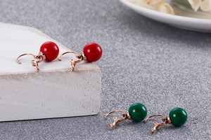 Gros plan de boucles d'oreilles perles rouges et vertes avec crochets or rose