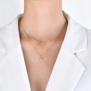 Close-up of golden double-layer necklace featuring a sparkling rhinestone P pendant on model
