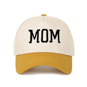 Detail of MOM embroidery on a beige and mustard yellow trucker baseball cap