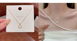 Detail of gold bow necklace with white shell pendant and zircon stones on a model