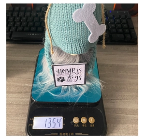 Detail showing knit gnome ornament with dog sign on a digital scale for weight check