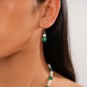 Close-up of minimalist hook earrings with elegant white pearl and green agate beads