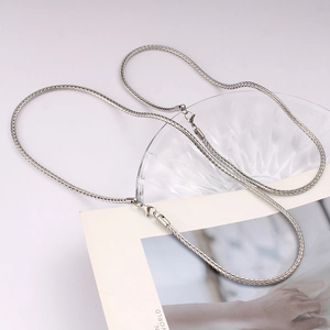 Silver foxtail chain sweater necklace with geometric design on fashion magazine backdrop