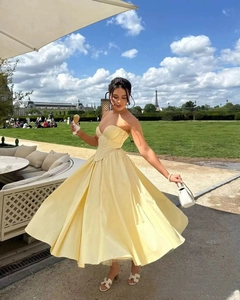 Detail of yellow corset maxi dress featuring a bow and lace-up back against Eiffel Tower
