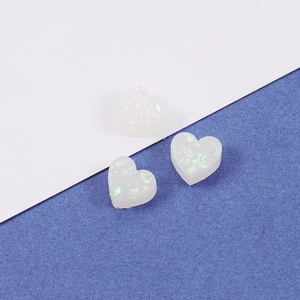 Macro view of three heart-shaped iridescent white opal charms for DIY jewelry making