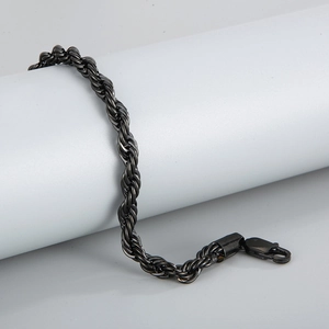 Macro detail of black nickel twist rope chain bracelet on white cylindrical display stand