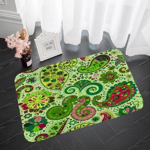 Rechteckige grüne Badematte mit Paisley-Blumenmuster auf dunklem Holzboden im Licht