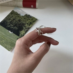 Detailed view of a silver bow-knot ring on a model hand with a lifestyle background