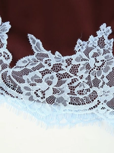 Gros plan détaillé de dentelle bleu clair sur tissu bordeaux avec motifs de fleurs