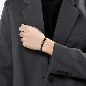 Close-up of black braided leather bracelet with magnetic steel clasp and bamboo charms