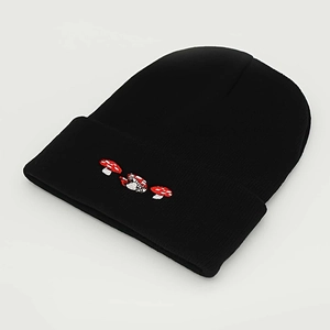 Close-up of red and white mushroom embroidery on a black cuffed knit beanie cap