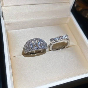 Detailed close-up of zircon bow ring and geometric cutout band in a velvet jewelry box