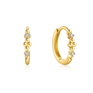 Macro detail of gold-plated geometric hoop earrings with sparkling cubic zirconia pavé