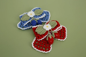Detail of handmade crochet bow hair clips with 3D strawberry and floral knitting textures