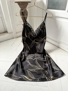 Détail de nuisette en soie noire avec motifs de feuilles dorées et décolleté en V dentelle