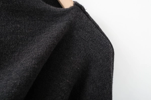 Detail of dark grey knit texture and collar design on a wooden hanger background