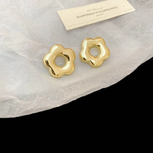 Gros plan de boucles d'oreilles fleurs dorées polies avec une finition métallique brillante