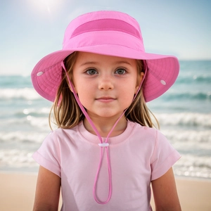 Pink kids sun hat with breathable mesh and adjustable chin strap on a sunny beach