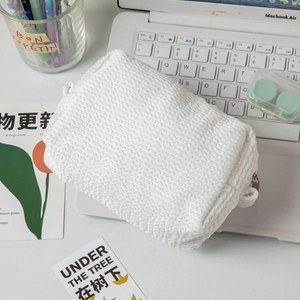 Detail view of the white waffle-texture cotton cosmetic bag on a desktop setup