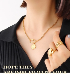 Close-up of 18K gold-plated coin necklace and minimalist rings on model with black background