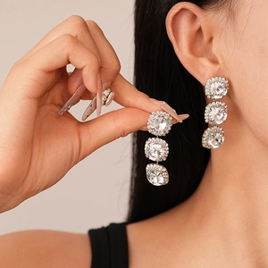 Macro view of silver triple round rhinestone drop earrings with detailed pavé settings