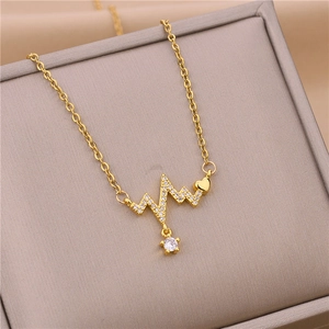 Close-up of golden heartbeat necklace with small heart and CZ pendant on soft cushion
