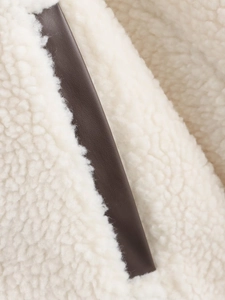 Detailansicht aus cremefarbenem Teddyfell und dunkelbrauner Lederpaspel an der Jacke
