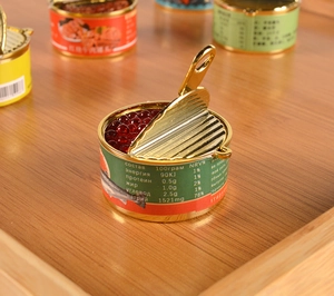 Macro shot of miniature red caviar tin with realistic beads and golden metal pull tab