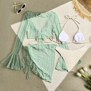 Flat lay of a 4-piece lace bikini set with green cardigan and white tulip accessories