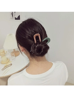 Close-up of U-shaped hair pins in pink and green colors used for elegant bun hairstyles