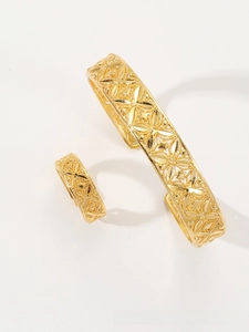 Macro shot of gold-plated bangle and ring set with intricate hollow floral patterns