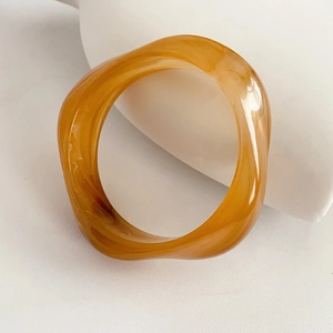 Detailed close-up of amber resin twisted bangle with fluid texture and glossy finish