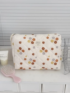 Detail der gesteppten Cord-Kosmetiktasche mit Blumendruck und stilvollem Webetikett