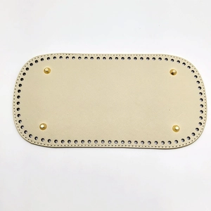 Close-up of cream oval DIY bag base with cross-grain texture and gold metal feet
