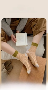 Détail de chaussettes rayées en coton jaune gingembre et vert sauge sur un mannequin