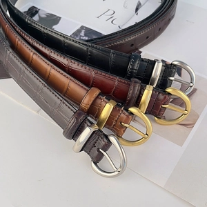Set of four vintage crocodile pattern leather belts in black, brown, and grey with metal buckles