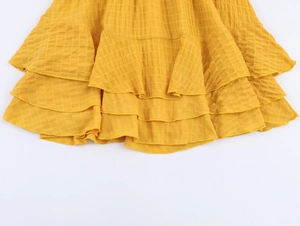 Dettaglio dell'orlo giallo a balze con volant su vestito corto estivo leggero