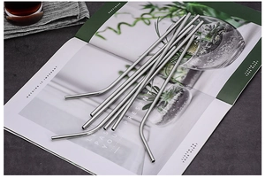 Detail of straight and curved stainless steel straws placed on an aesthetic magazine page